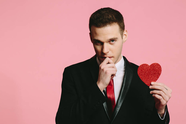 schöner Mann im schwarzen Anzug mit rotem Herz zum Valentinstag - Foto, Bild