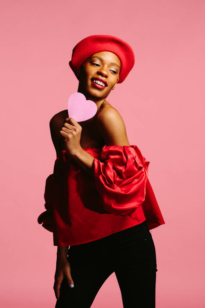 giovane donna attraente in rosso che tiene un cuore rosa, sii il mio Valentino - Foto, immagini