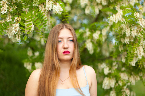 портрет девушки с длинными волосами плюс размер фигуры в окружении цветов акации на зеленом весеннем лугу
 - Фото, изображение