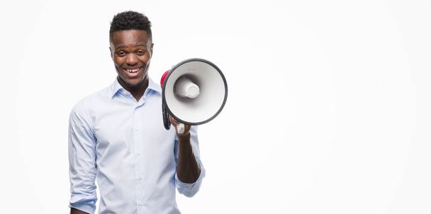Young african american man holding megaphone with a happy face standing and smiling with a confident smile showing teeth - Foto, imagen