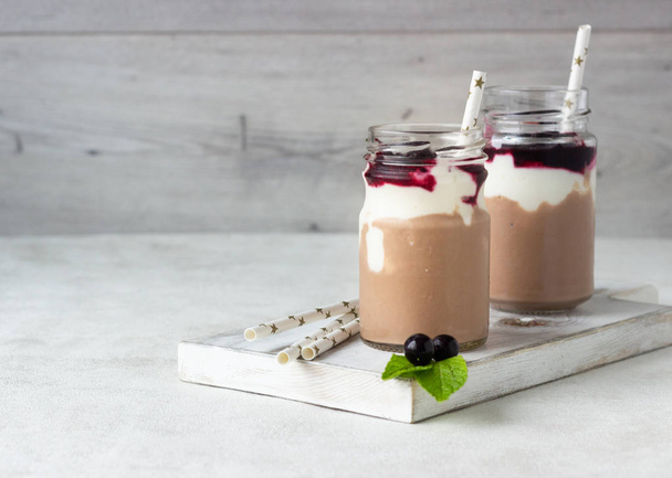 Two bottles of chocolate and banana smoothie with natural yoghurt and black currant. Delicious and healthy breakfast concept. Selective focus. Copy space. - Foto, immagini