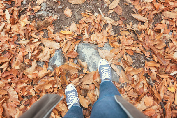 Herbst, Herbst, Blätter, Beine und Schuhe. konzeptionelles Bild von Beinen in Schuhen auf den Herbstblättern. Wanderschuhe in der Natur  - Foto, Bild