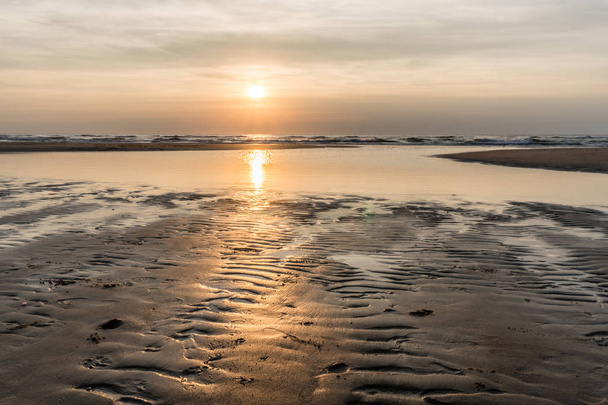 Stříbrný Sunset v Severním moři pláž Egmond aan Zee, Nizozemsko. Zapadající slunce odráží v kalužích a ribbles mokrý písek - Fotografie, Obrázek
