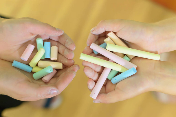 Montón de piezas de colores de tiza en las manos de las niñas
 - Foto, imagen
