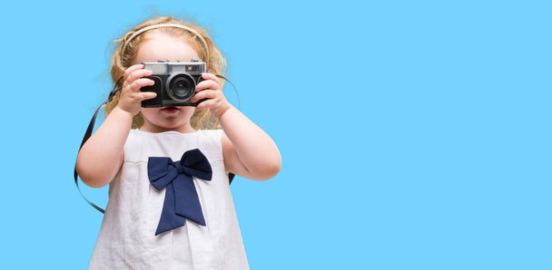Güzel sarışın yürümeye başlayan çocuk vintage fotoğraf makinesi ile fotoğraf çekmek - Fotoğraf, Görsel