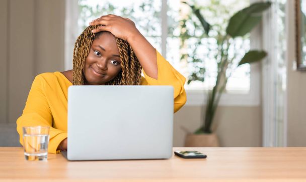 African american vrouw met laptop benadrukt met de hand op het hoofd, geschokt met schaamte en verrassing gezicht, boos en gefrustreerd. Angst en boos voor fout. - Foto, afbeelding