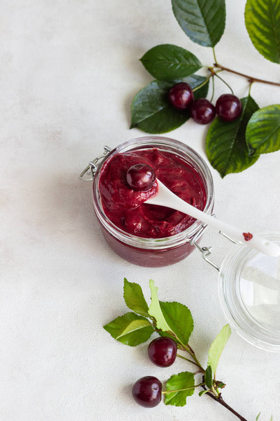 Homemade cherry jam in jars with fresh cherries on a light background. - Foto, immagini