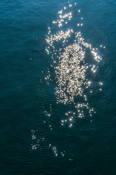 Αφαιρετικά σημεία που δημιουργούνται από το φως αντανακλά στο νερό των ωκεανών. - Φωτογραφία, εικόνα