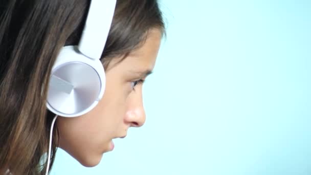 close-up background. A beautiful teenage girl on a colored background, in white headphones looks at the laptop screen. slow motion, 4k - Záběry, video