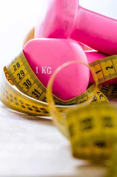 still life and close up with apple, pink weight, yellow tape measure. fitness and lifestyle concepts. - 写真・画像