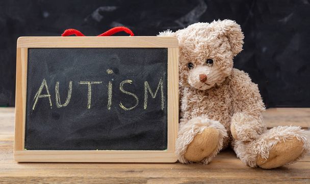 Autism and school. Teddy bear and a blackboard. Autism text drawing on the blackboard - Фото, зображення