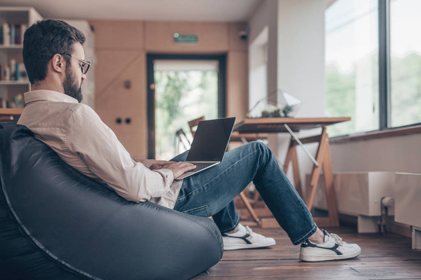 Jeune homme avec ordinateur portable au travail à l'intérieur
 - Photo, image