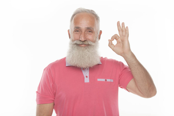 senior funny bearded man in pink t-shirt is shows gestures and grimaces. - Photo, Image