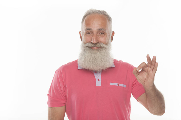 senior funny bearded man in pink t-shirt is shows gestures and grimaces. - Zdjęcie, obraz