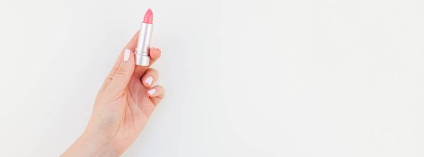 Nainen käsi pastelli manikyyri kiillottaa tilalla vaaleanpunainen huulipuna eristetty valkoisella pohjalla kopioi tilaa. Pitkä leveä banneri naisellinen kauneus blogi sosiaalinen media
 - Valokuva, kuva