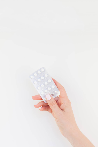 Mulher mão com manicure pastel polonês segurando pílulas em blister isolado em fundo branco com espaço de cópia. Modelo para as mídias sociais do blog de beleza feminina. Conceito de saúde feminina
 - Foto, Imagem