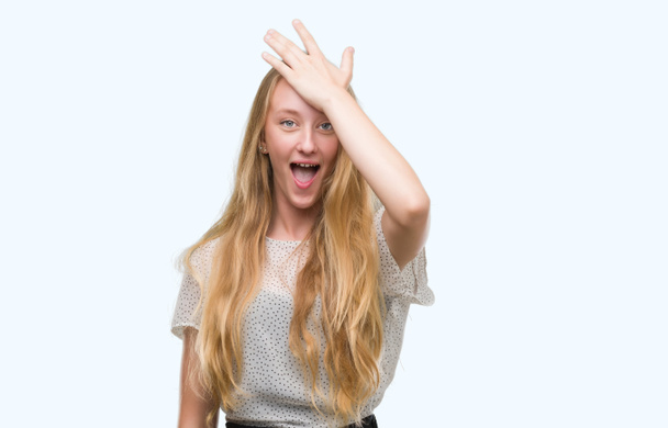 Blond dospívající žena nosí molů košile překvapen, s rukou na hlavu za chybu, nezapomeňte chyba. Zapomněl, špatné paměti koncept. - Fotografie, Obrázek