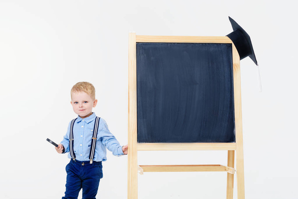 Back to school. Little child near a chalkboard on a white isolated background - Foto, Imagem
