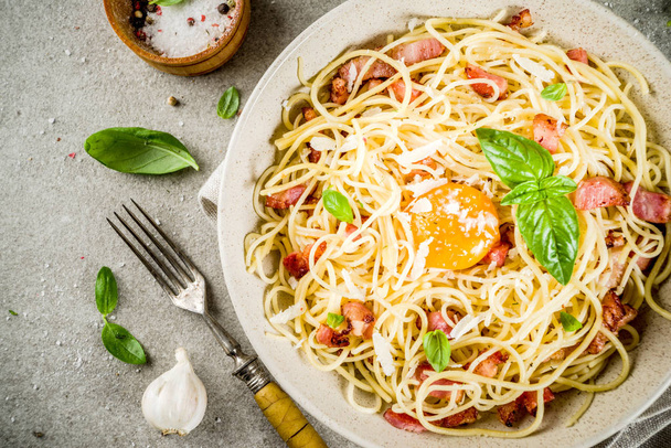 Традиційні італійські макарони, спагетті карбонара з беконом, вершковий соус, сир пармезан, яєчний жовток і свіжий базилік листя сірий камінь фонові копії простір - Фото, зображення