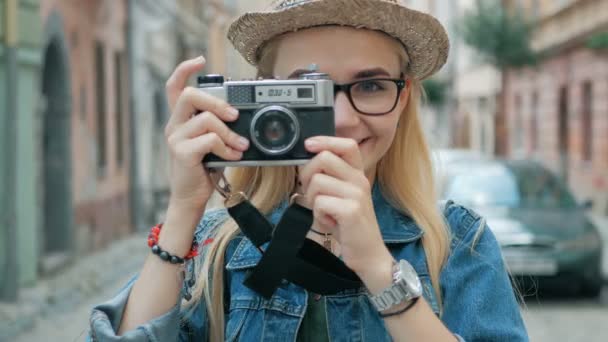 Young woman tourist taking a picture on retro camera of a city on vacation - Séquence, vidéo