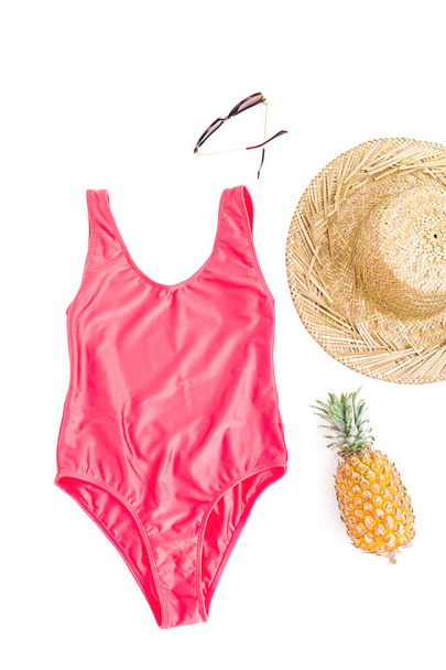 Frutas de abacaxi, óculos de sol, chapéu de palha e roupa de banho rosa sobre fundo branco. Deitado plano, vista superior. Conceito de praia
. - Foto, Imagem