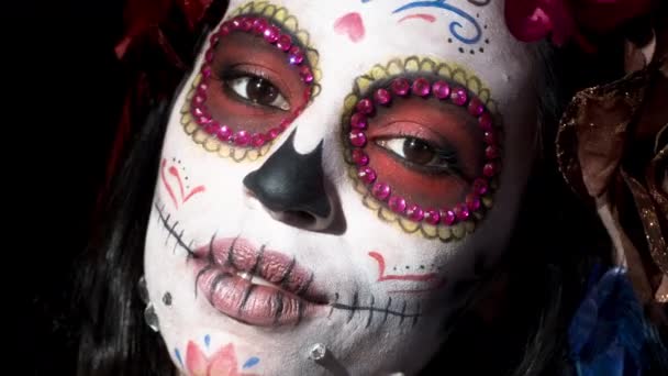 beautiful woman with custom designed candy skull mexican day of the dead face make up on black background - Footage, Video