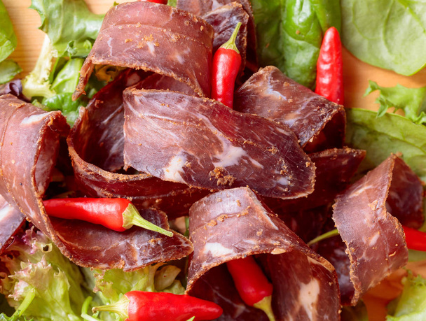 Healthy dry beef jerky with herbs and small red peppers. Top view. - Photo, Image