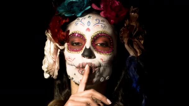 beautiful woman with custom designed candy skull mexican day of the dead face make up on black background - Footage, Video