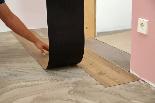 Work on laying flooring. Worker installing new vinyl tile floor. - Photo, Image