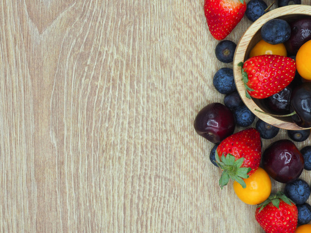 Frutas frescas de verano, cereza, fresa, grosella y arándano en plato de madera aislado sobre fondo blanco
. - Foto, Imagen