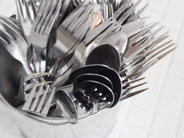Cuchara y tenedor de acero inoxidable están incluidos en los tanques de acero inoxidable sobre la mesa
. - Foto, Imagen