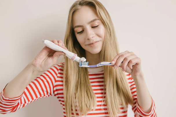Tutan bir diş fırçası ve diş macunu beyaz bir arka plan üzerinde izole yerleştirerek gülümseyen kadın - Fotoğraf, Görsel