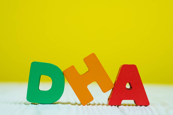 DHA text alphabet on white wooden table. yellow wall background with copy space for add text. - 写真・画像