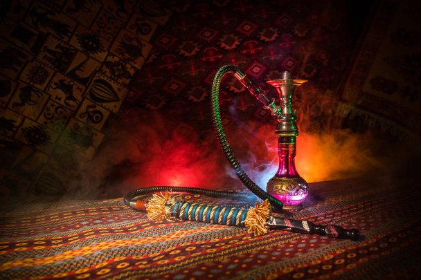 Shisha glühende Kohlen auf Shisha-Schüssel machen Dampfwolken im arabischen Inneren. orientalische Ornamente auf dem Teppich. stilvolle orientalische Shisha im Dunkeln mit Hintergrundbeleuchtung. für Shisha-Werbung. Selektiver Fokus - Foto, Bild