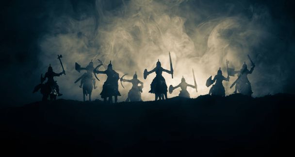 騎兵と歩兵の中世の戦闘シーン。個別のオブジェクトとして人物のシルエットは、暗いトーンの霧の背景に戦士の間戦います。夜のシーン。選択と集中 - 写真・画像