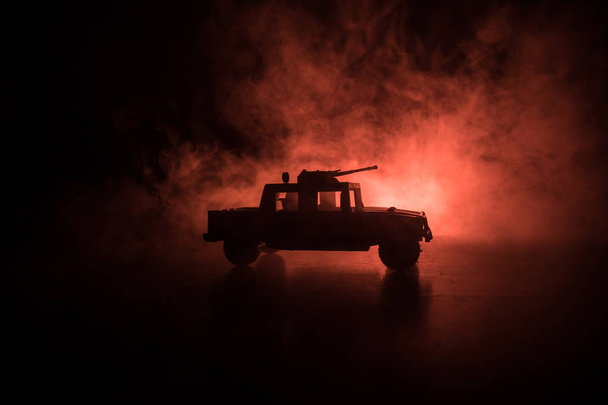 Military patrol car on dark toned foggy background. Army war concept. Silhouette of armored vehicle with gun in action. Decorated. Selective focus - Photo, Image
