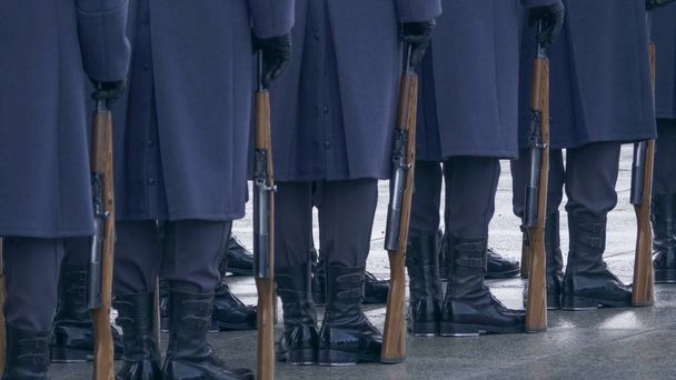 Soldaten in blauen Uniformen und schwarzen Stiefeln, die ein Gewehr in der Hand halten und in einer Reihe stehen. - Foto, Bild