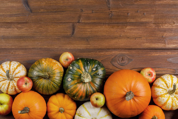 Many orange pumpkins and apples on wooden background, Halloween concept - Foto, afbeelding