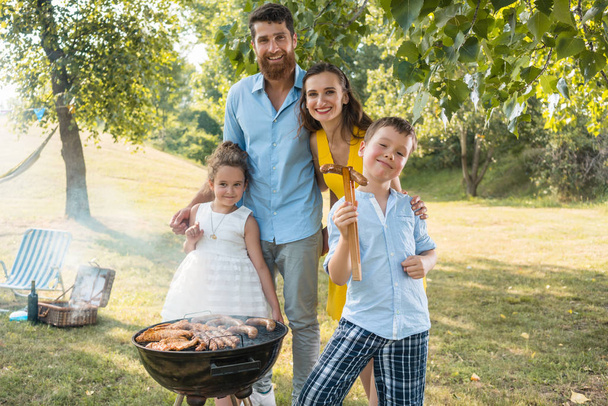 Portrait de famille heureuse avec deux enfants debout à l'extérieur
 - Photo, image