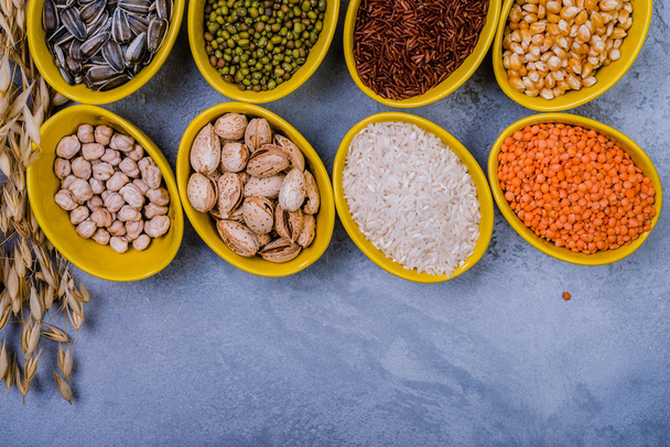 Cereales surtidos, frijoles, semillas en cuencos sobre mesa de hormigón gris, aplanado
 - Foto, Imagen