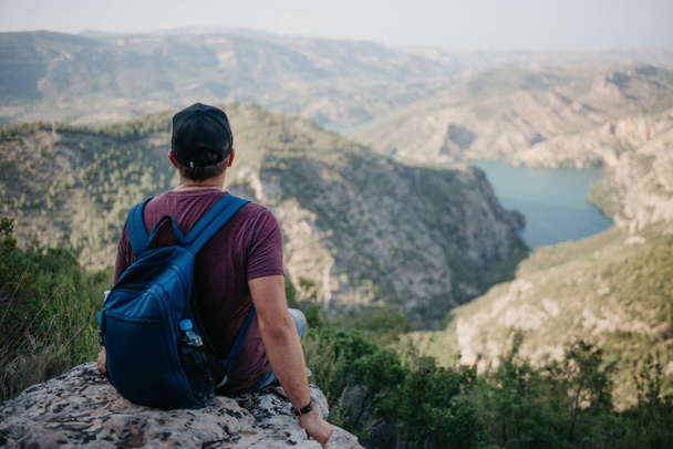 Людина з рюкзак, сидячи на камінь красиві ущелини із смарагдових річка на заході сонця в Іспанії. Пригоди людини. - Фото, зображення