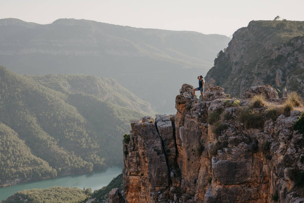 Un hombre musculoso buscando algo en el cañón con un río esmeralda al atardecer en España. Viajero en las montañas
. - Foto, Imagen