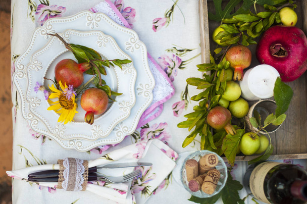 Lunch is romantic in autumn garden, atmosphere of holiday and coziness. Autumnal dinner in the open air with wine and fruit. Decor table with flowers and pomegranate. Vintage photo. - Фото, зображення