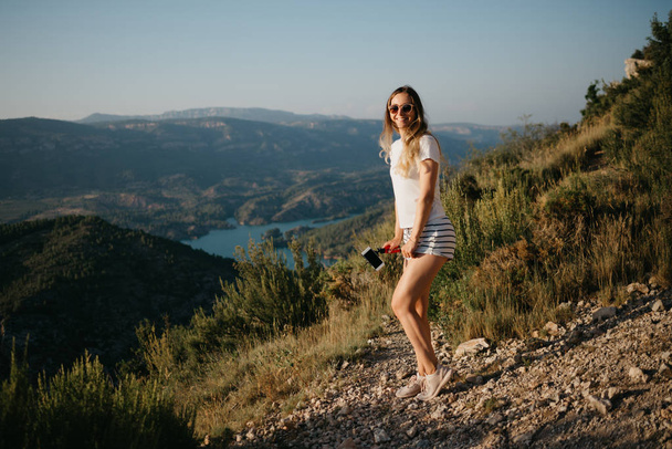 Милою дівчиною, що танцює на піщаному дорозі з Каньйон і смарагдовий озеро на фоні на захід сонця в Іспанії. Мандрівник у горах. - Фото, зображення