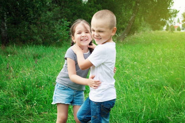 男の子と女の子の子供たちは、自然で遊んでいます。少年は、少女を抱いています。子供たちは楽しんで、笑って - 写真・画像