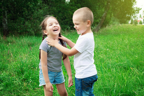 I bambini - un ragazzo e una ragazza stanno giocando in natura. Il ragazzo sta abbracciando la ragazza. I bambini si divertono e ridono
 - Foto, immagini