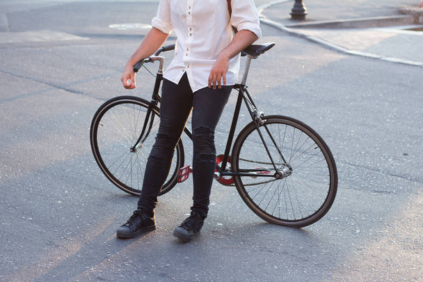Young modern buisinessman with black bicycle on morning city streets,stylish beared hipster  - Фото, зображення
