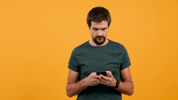 Mann in lässigem T-Shirt tippt und zupft auf seinem Smartphone - Filmmaterial, Video