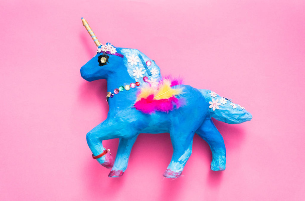 Kids craft. Painted blue and decorated with jewels and feathers paper mache unicorn. - Photo, Image