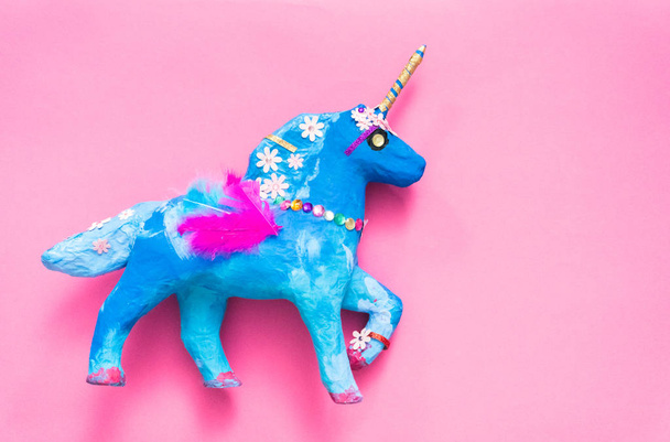 Kids craft. Painted blue and decorated with jewels and feathers paper mache unicorn. - Fotó, kép